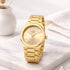Gold wristwatch on a marble surface with a soft white background
