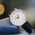 Rose gold ladies watch with black leather strap resting on fabric blocks